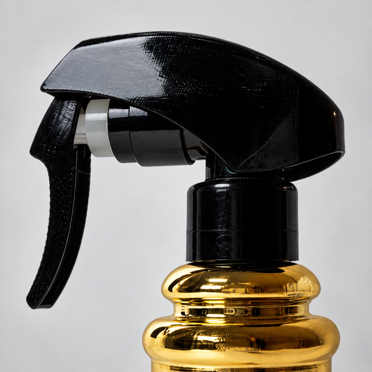 Close-up of the black trigger and gold neck of the MV Barbershop Pole Spray Bottle.