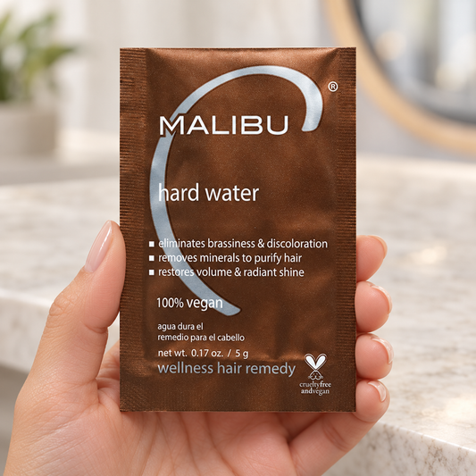 Malibu C Hard Water Wellness Remedy 5g sachet held at the edges, with the front label visible.