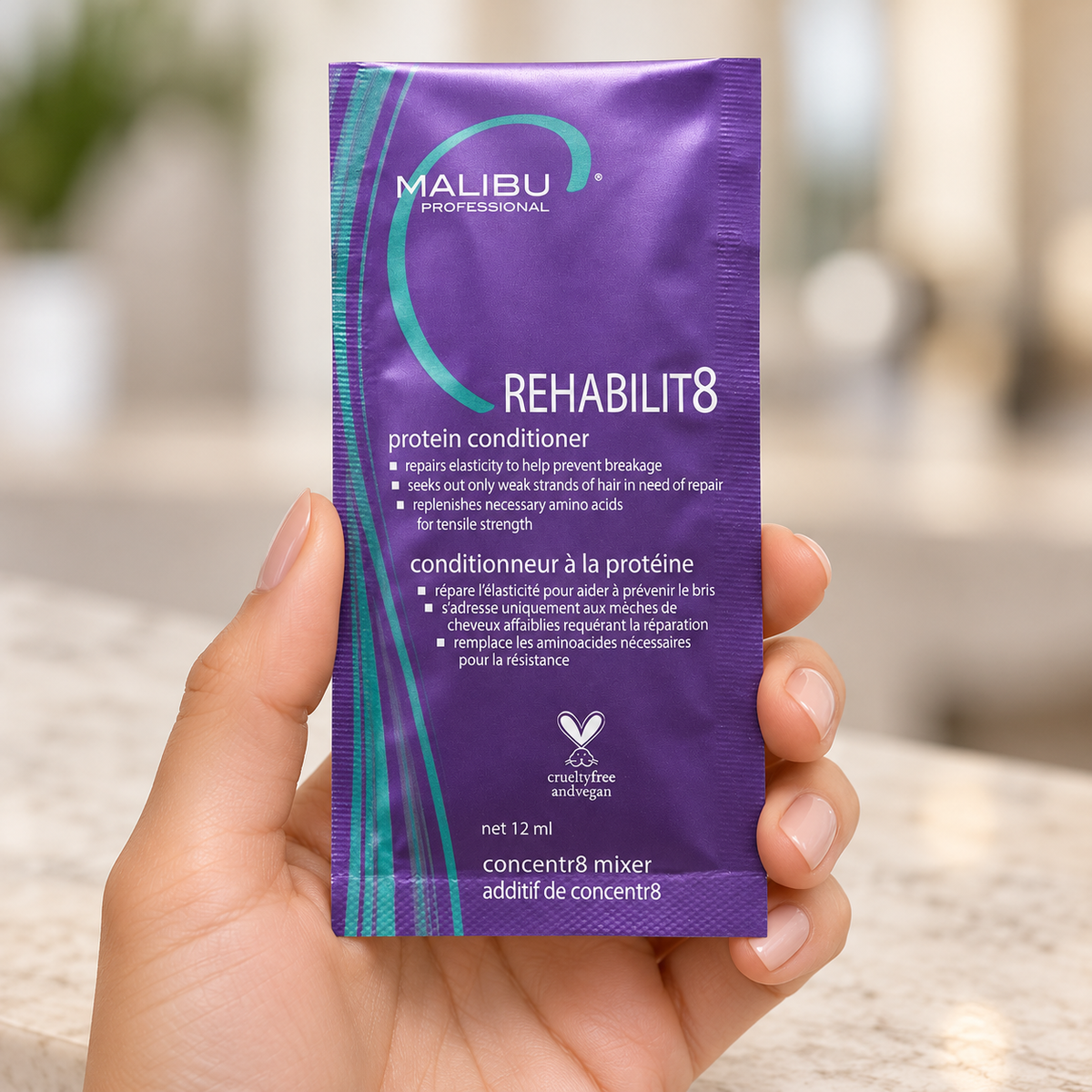 Malibu C Rehabilit8 Protein Conditioner 12ml sachet held at the edges in a salon.
