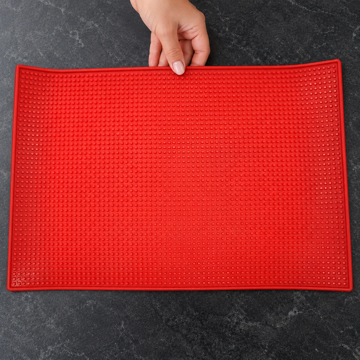 Red textured barber mat being positioned on a clean salon worktop