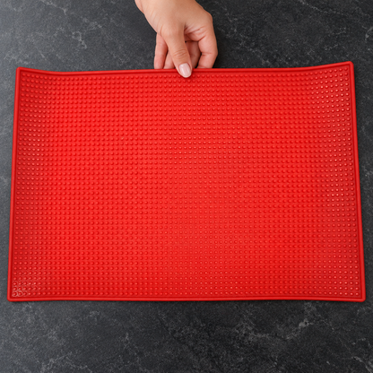 Red textured barber mat being positioned on a clean salon worktop