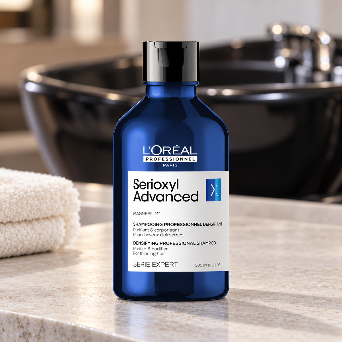 L’Oréal Professionnel Serioxyl Advanced 300 mL shampoo bottle beside a salon washbasin.