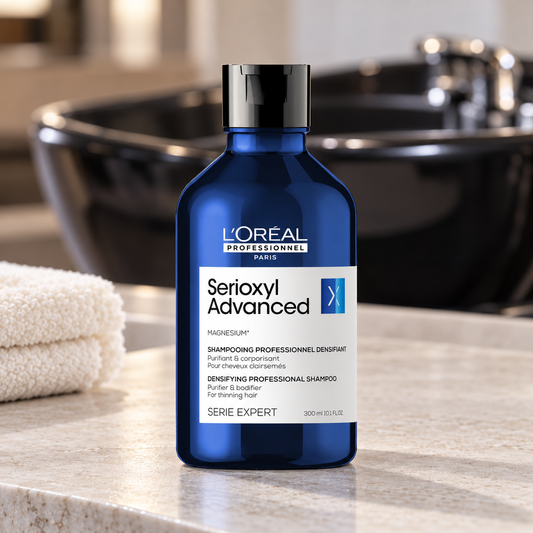 L’Oréal Professionnel Serioxyl Advanced 300 mL shampoo bottle beside a salon washbasin.