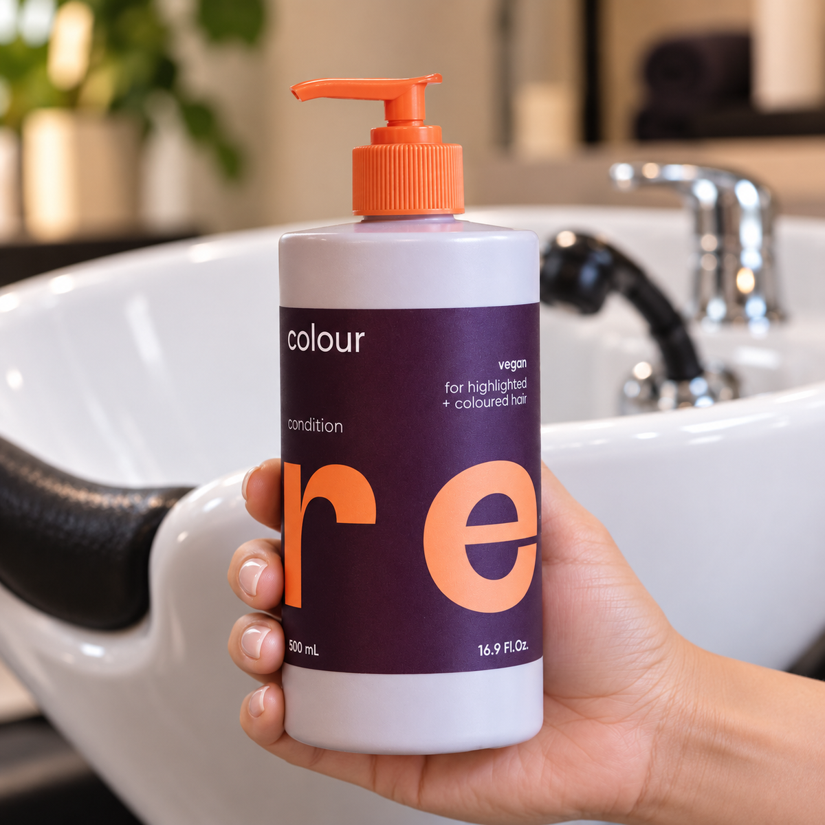 NAK CARE Colour Conditioner 500ml held beside a salon wash basin.