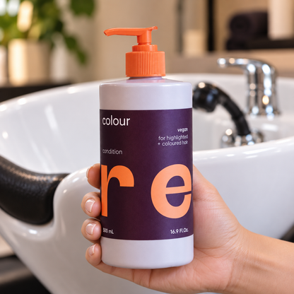 NAK CARE Colour Conditioner 500ml held beside a salon wash basin.