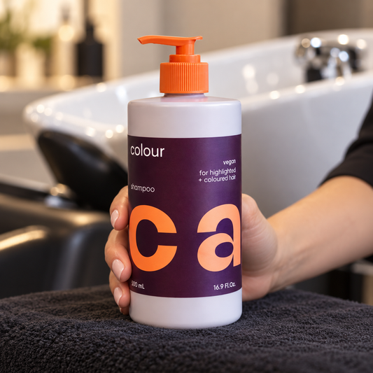 NAK CARE Colour Shampoo 500ml held beside a salon wash basin.