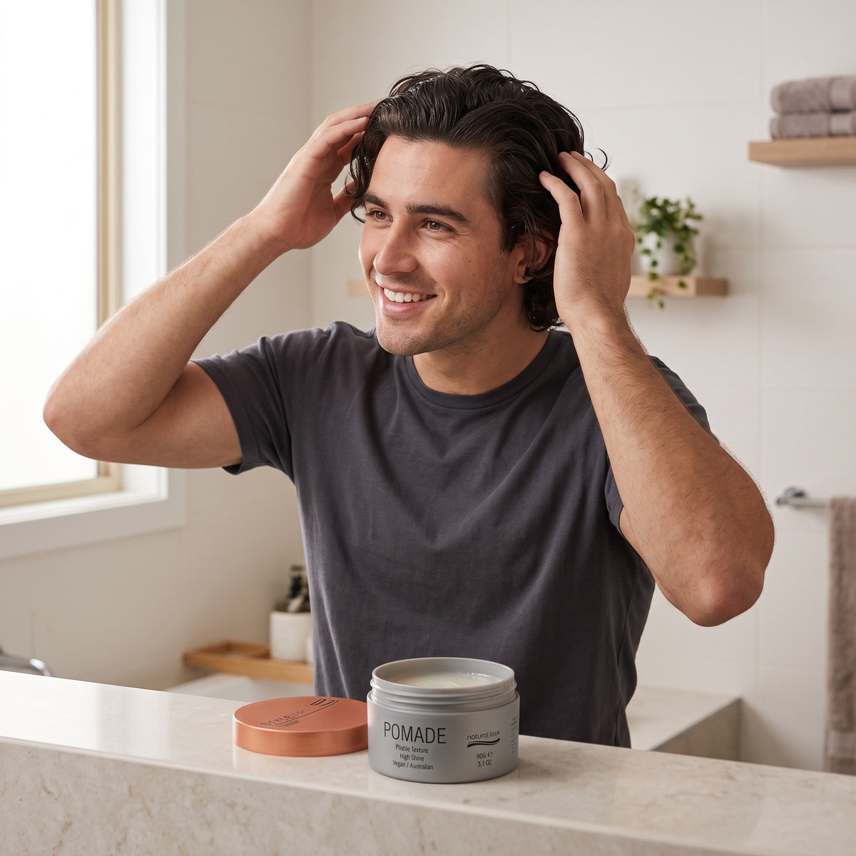 Man styling his hair beside a Natural Look Pomade tin