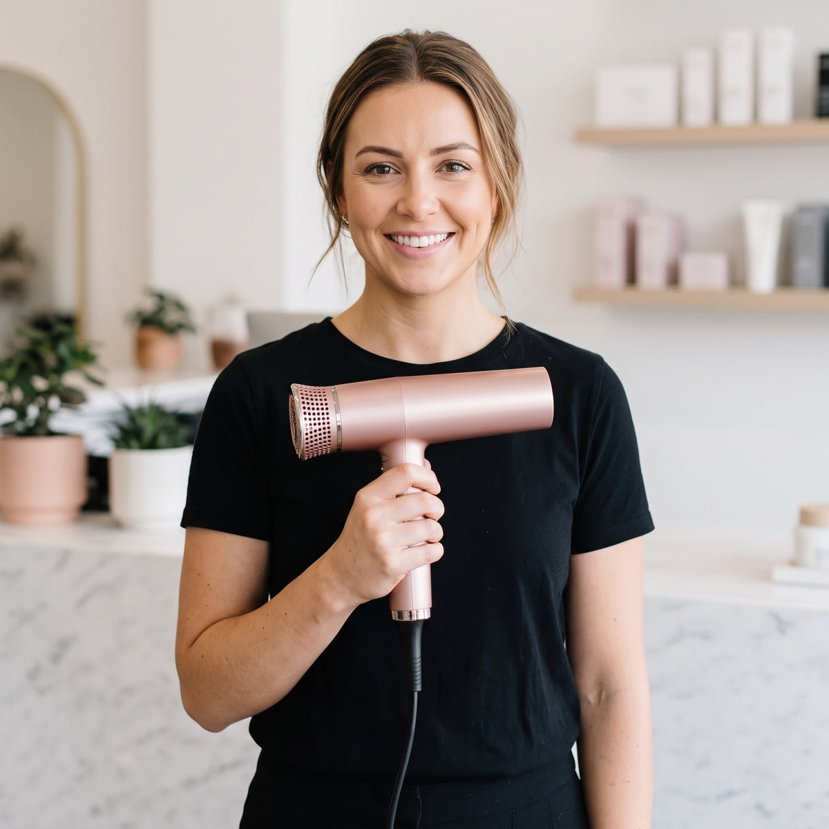 Stylist holding the Pro-One Aerolite Rose Gold hairdryer in a salon