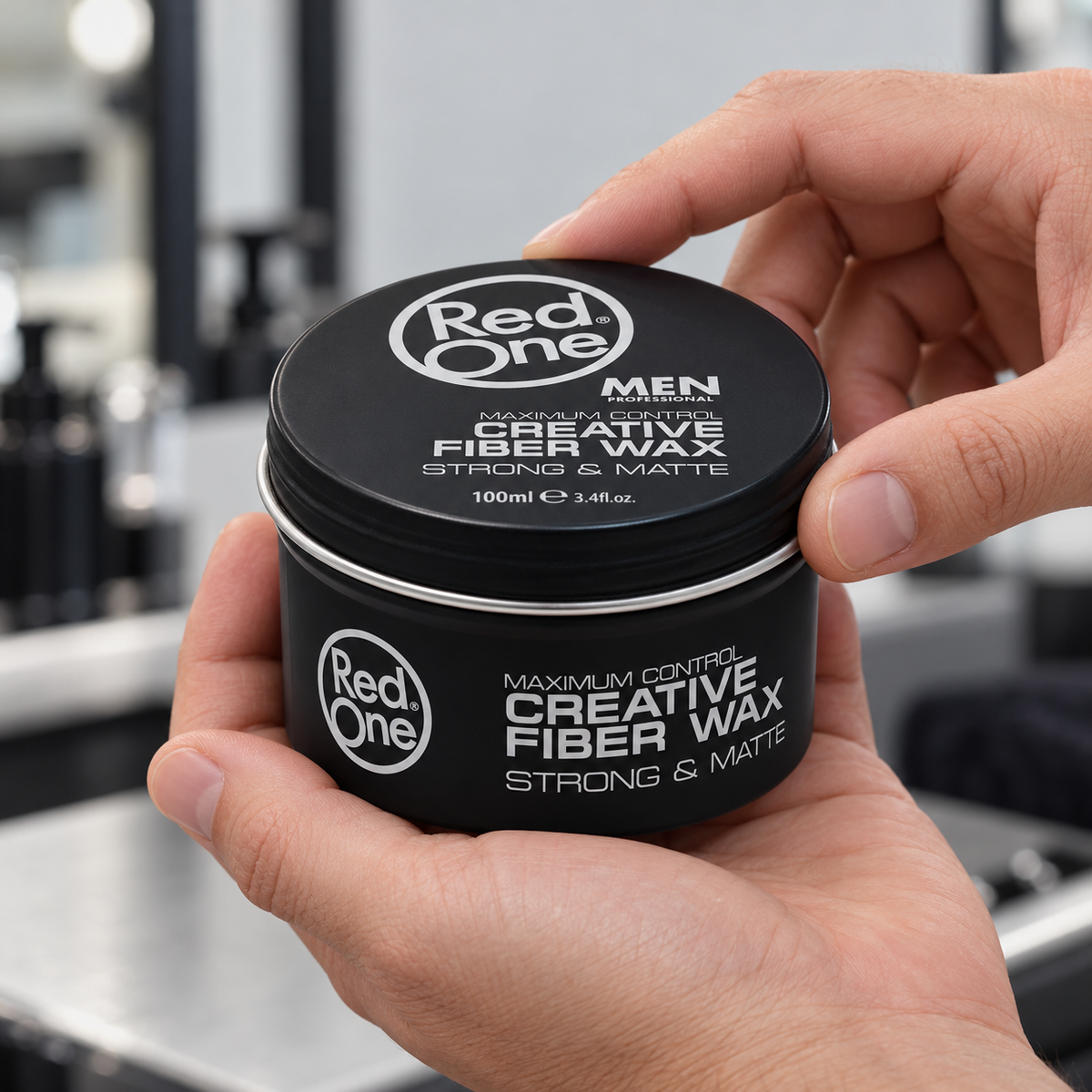 Hands holding RedOne Creative Fiber Wax Strong and Matte 100ml, showing the screw lid and front label.
