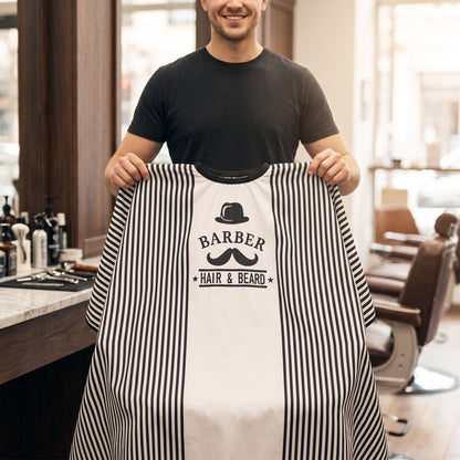 Barber holding up the RedOne Moe+Hat striped cape