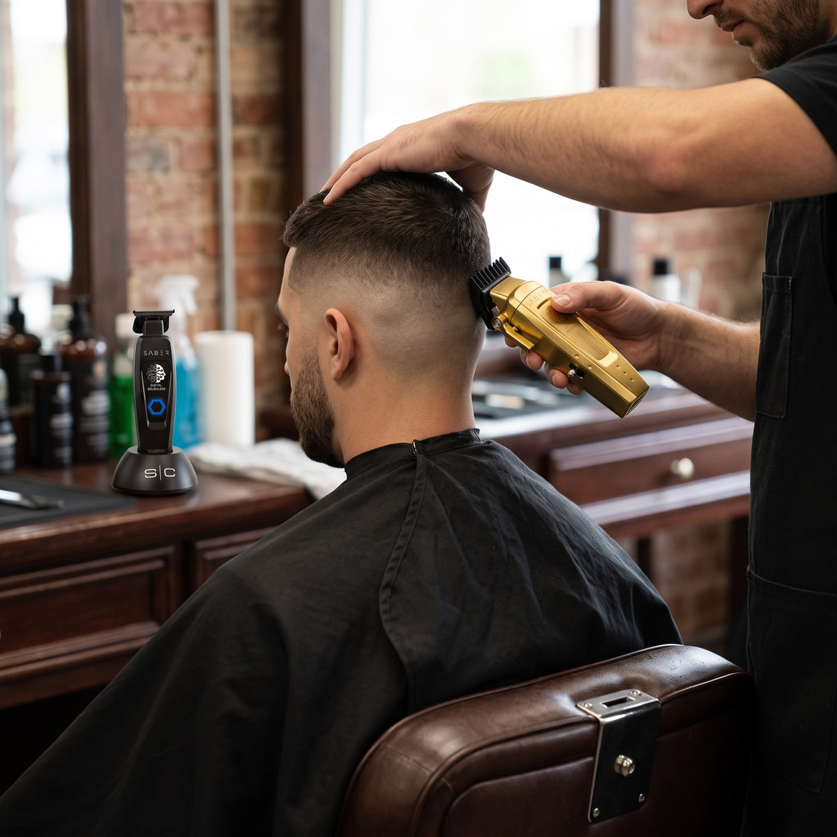 Barber fading a client with the gold StyleCraft Saber 2 clipper